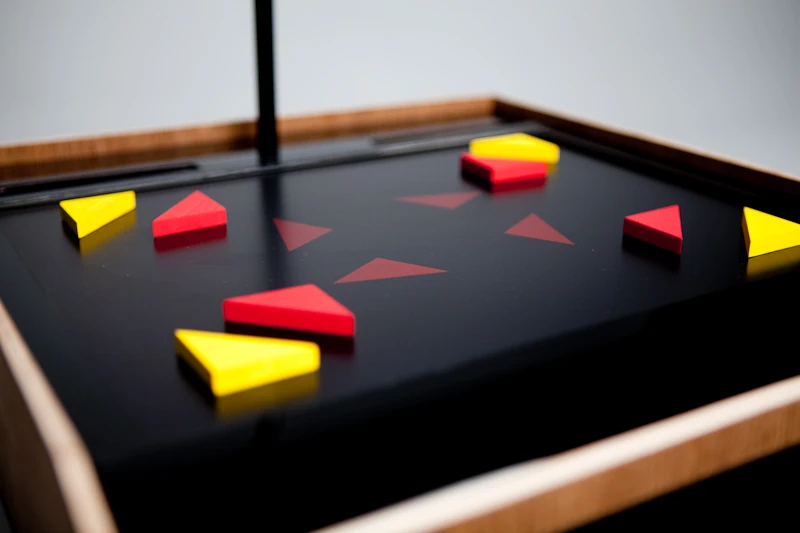 A child arranges corresponding colored blocks over the shapes. With the pieces in place, the "record" button is pressed, and the camera above, which points down at the screen, takes a snapshot