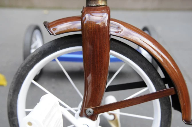 New Zealand's Rob Pollock hand-paints clients' bicycle (or tricycle) frames with a faux woodgrain finish