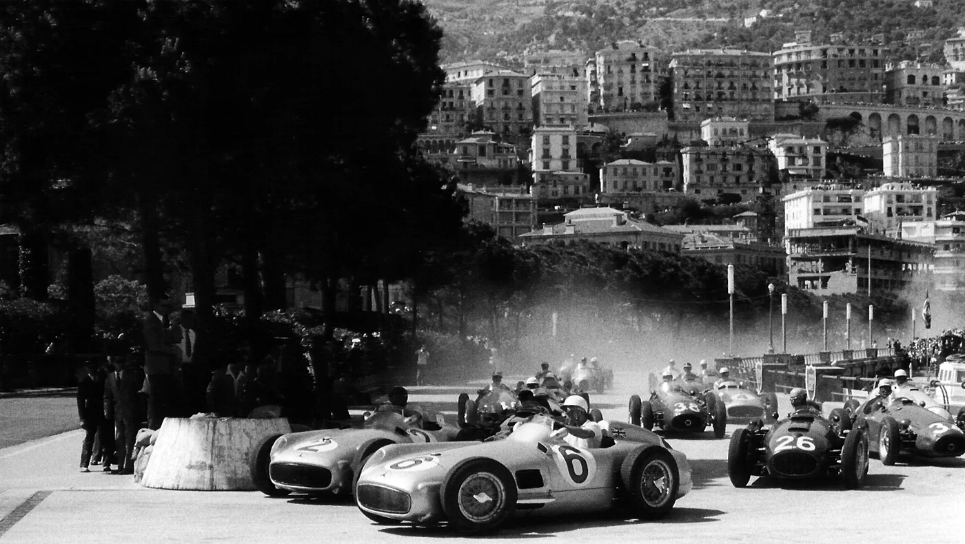 Juan Manuel Fangio and Stirling Moss battle for the lead on the first lap of the Monaco Grand Prix, both in Mercedes-Benz. Fangio's car subsequently set a world record at auction