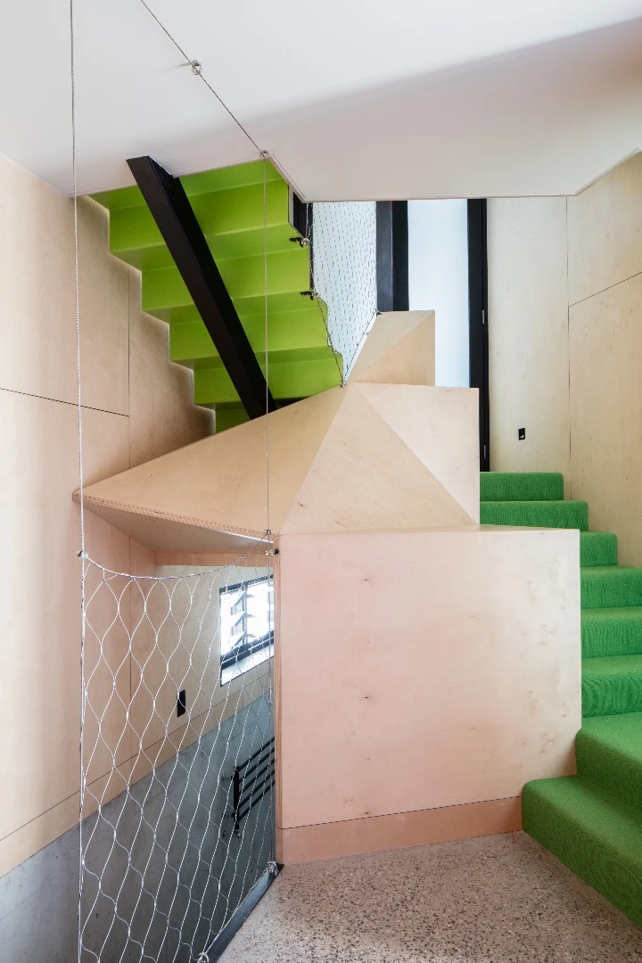 The architects attempted to mitigate the lack of garden in the Acute House with lawn green carpets, hanging plants, a central aquarium, and a balcony