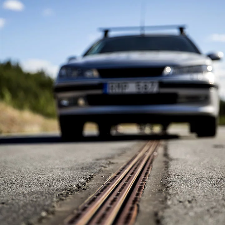 In the eRoadArlanda project, electricity is fed from parallel tracks in the road into a vehicle through a retractable arm attached to the bottom of the car