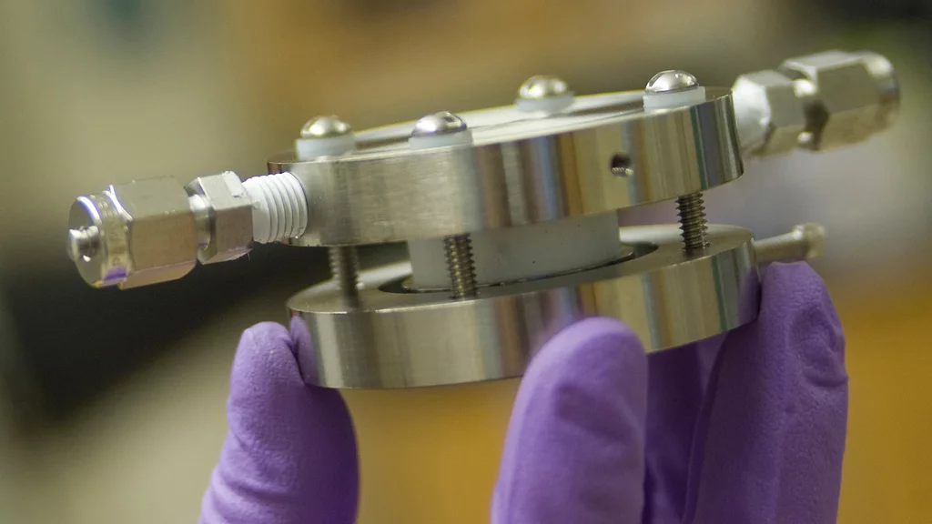 An experimental lithium-air battery developed at MIT has inlet and outlet on the sides to provide a flow of air, providing oxygen for the battery's operation (Image: Patrick Gillooly/MIT)