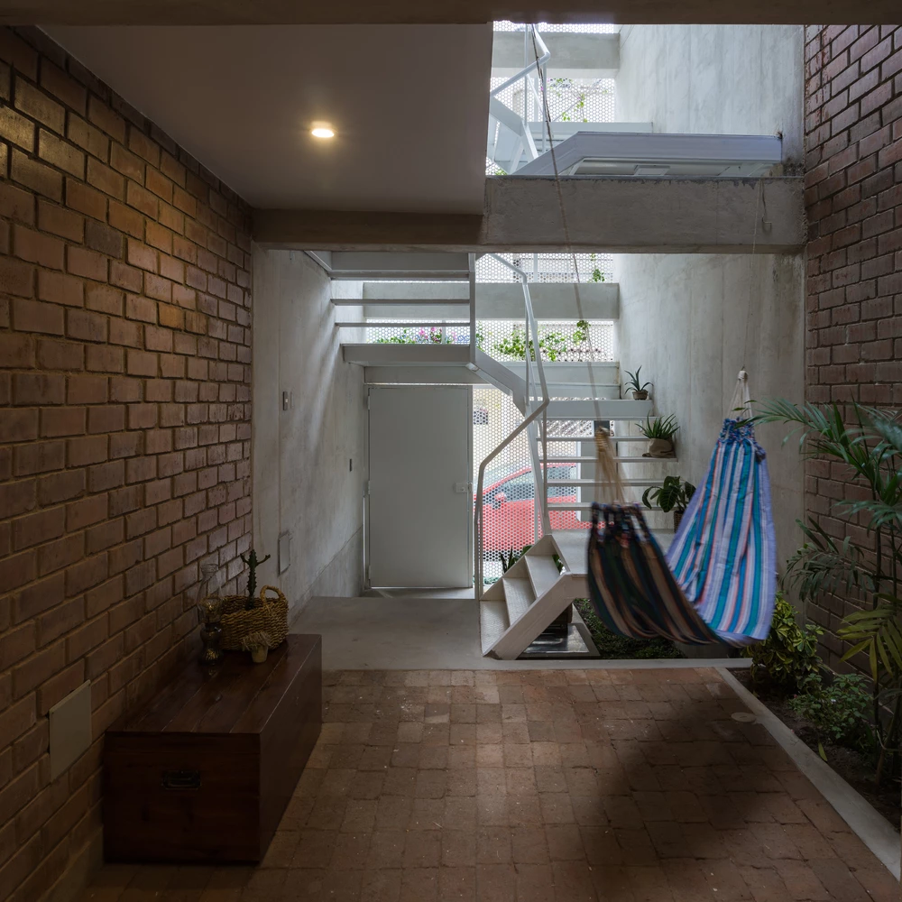 The interior design boasts cool elements like exposed brick, concrete, white metal, and lush green vegetation