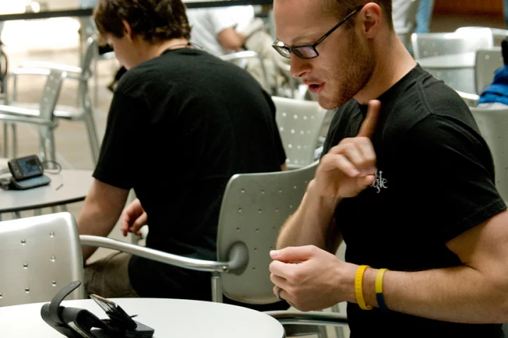 Josiah Cheslik, a UW junior and volunteer in the MobileASL field study, demonstrates using the phone to sign with Pete Michor, seen in the background, another participant in the study (Image: Mary Levin, UW)