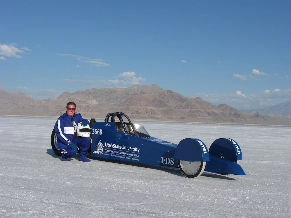 USU biochemist Michael R. Morgan posing beside the Aggie A-Salt Streamliner he piloted at Utah's Salt Flats (Photo: USU)