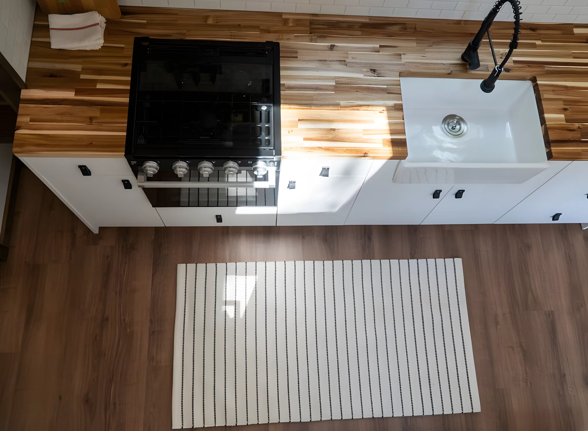 The Olympic's kitchen includes a three-burner propane-powered stove, an oven, a farmhouse-style sink, and a fridge/freezer