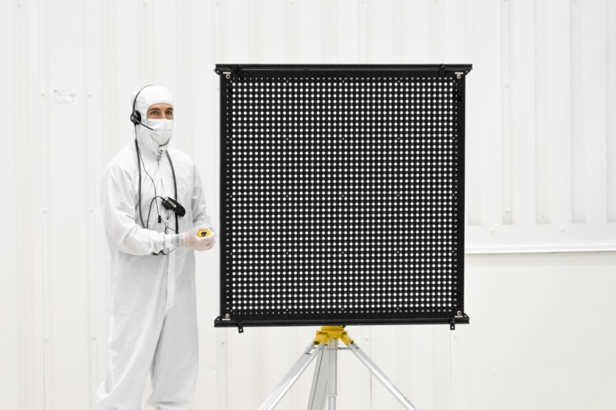 Engineer Chris Chatellier stands next to a target board with 1,600 dots