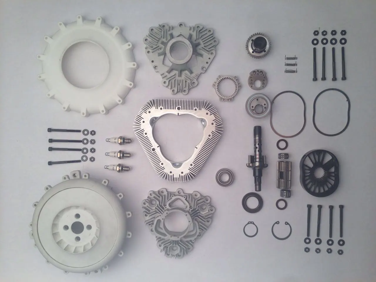 The engine's parts in their entirety, showcasing its simplicity – to the right are the central rotary parts, with the oval-shaped to rotor to the right of the shaft; the holes at bottom allow for air intake while the holes at top allow for exhaust expansion to eliminate the need for a muffler