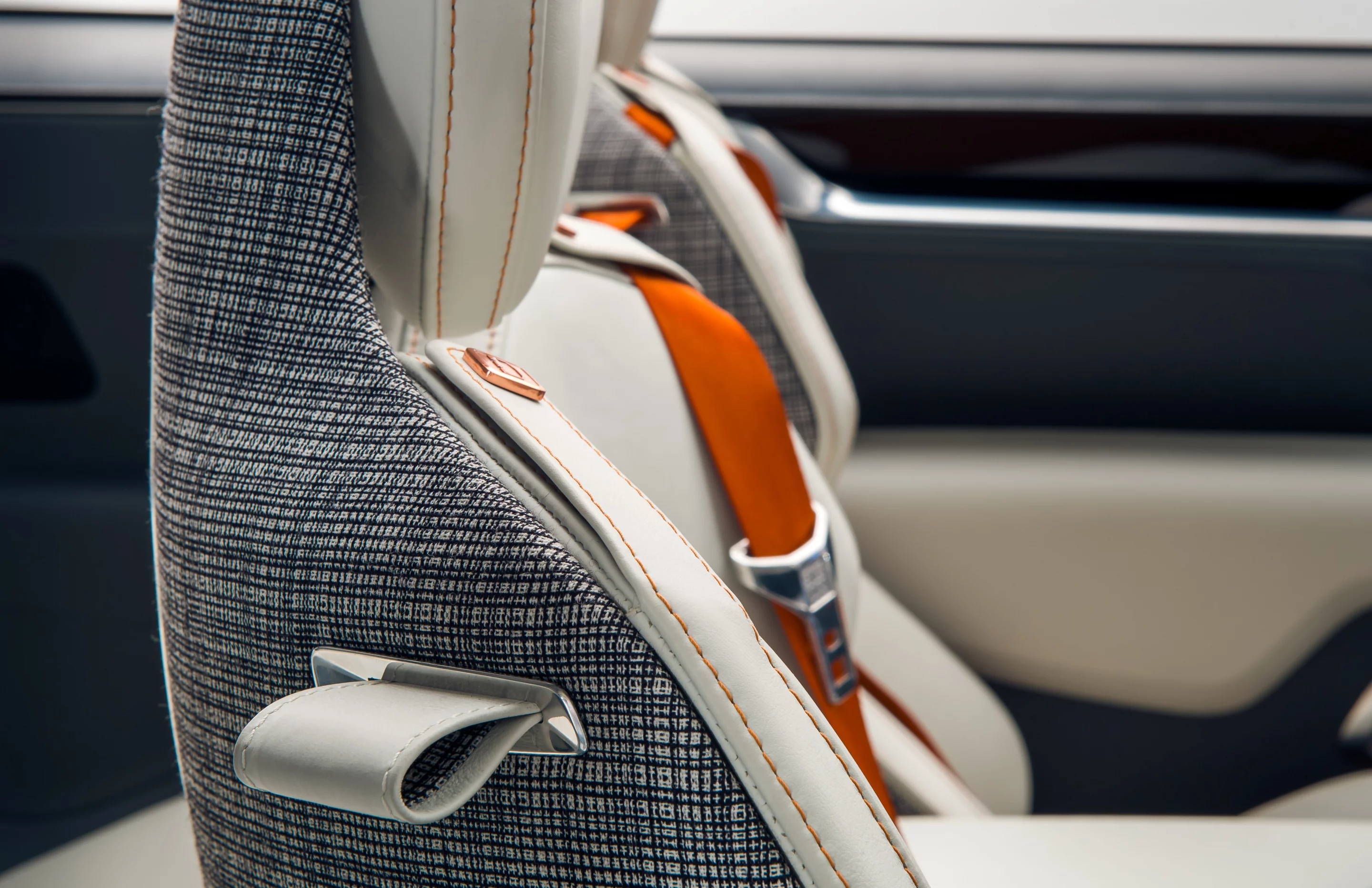 Checkered black and white wool on headliners and seat sides, plus orange seatbelts are clear signs of the retro Scandinavian design influence