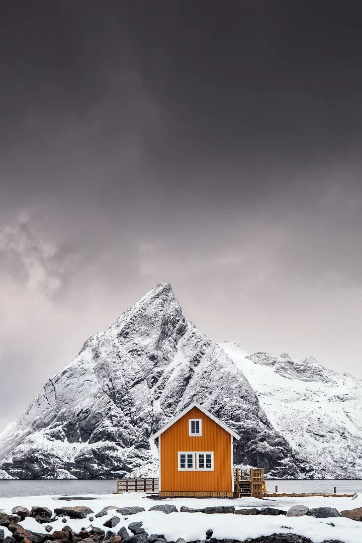 The beautiful Mount Olstinden has almost the same shape as the roof of this cute yellow cabin and the yellow color creates some amazing contrast to the snow covered mountain. This place can be found in the Lofoten Archipelago at the small island named Sakrisøy