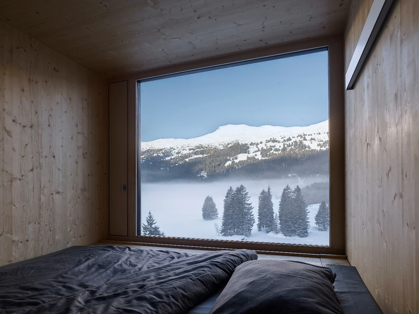 With a bed running from wall-to-wall and an end facing the lake through a floor to ceiling window, the modular rooms making up Switzerland's Revier Mountain Lodge are designed to mimic the camper van experience