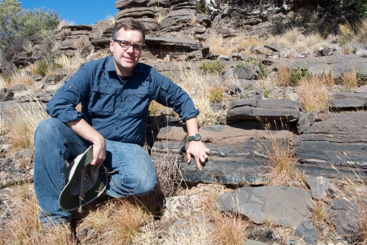 Professor Andrew Czaja shows the layer of rock where the bacteria were discovered