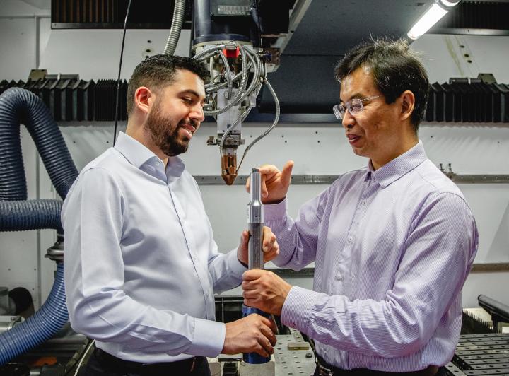 Researchers Carmelo Todaro and Ma Qian inspect a 3D-printed titanium alloy cube