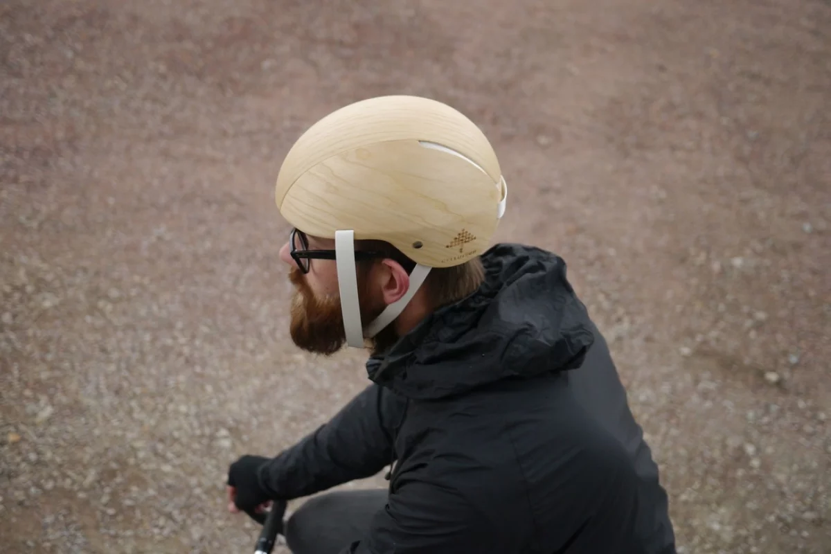 The helmet features a wood outer veneer, wood-based foam on the inside, and paper straps