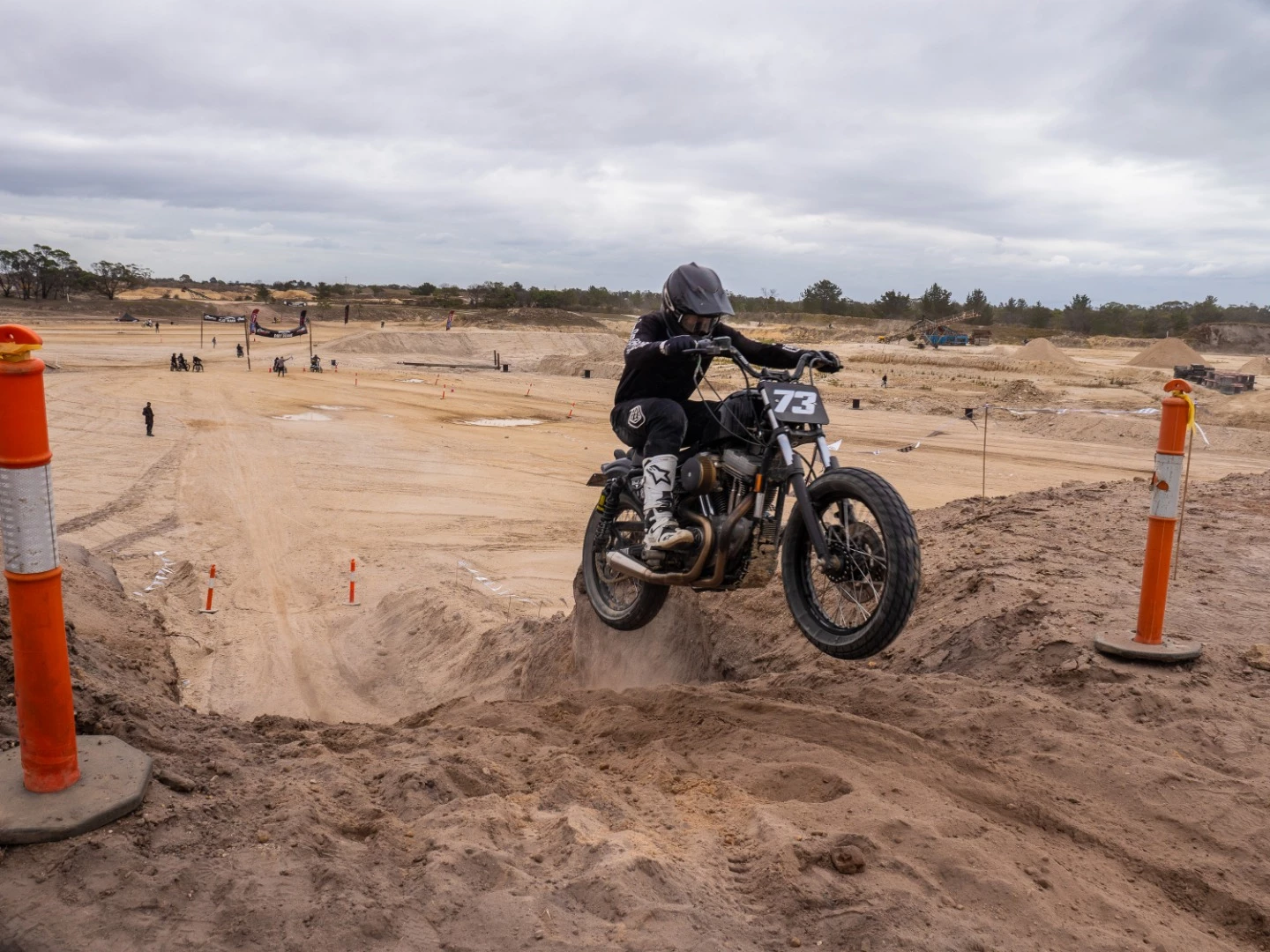 That's how we do it! Flat track styled Harley takes a leap at the end of a successful hill climb