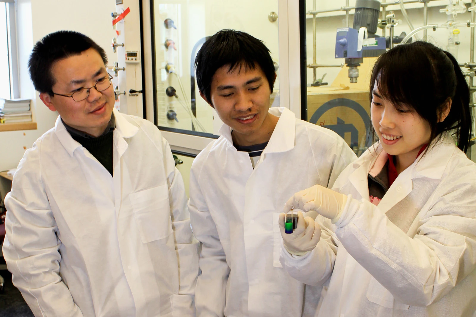 The research team holding a solution of iron oxide particles that changes color when an external magnetic field is applied to it