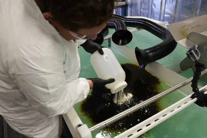 A PNNL researcher puts the chemically modified sawdust to work on a small oil spill inside a lab that mimics the Arctic's icy conditions