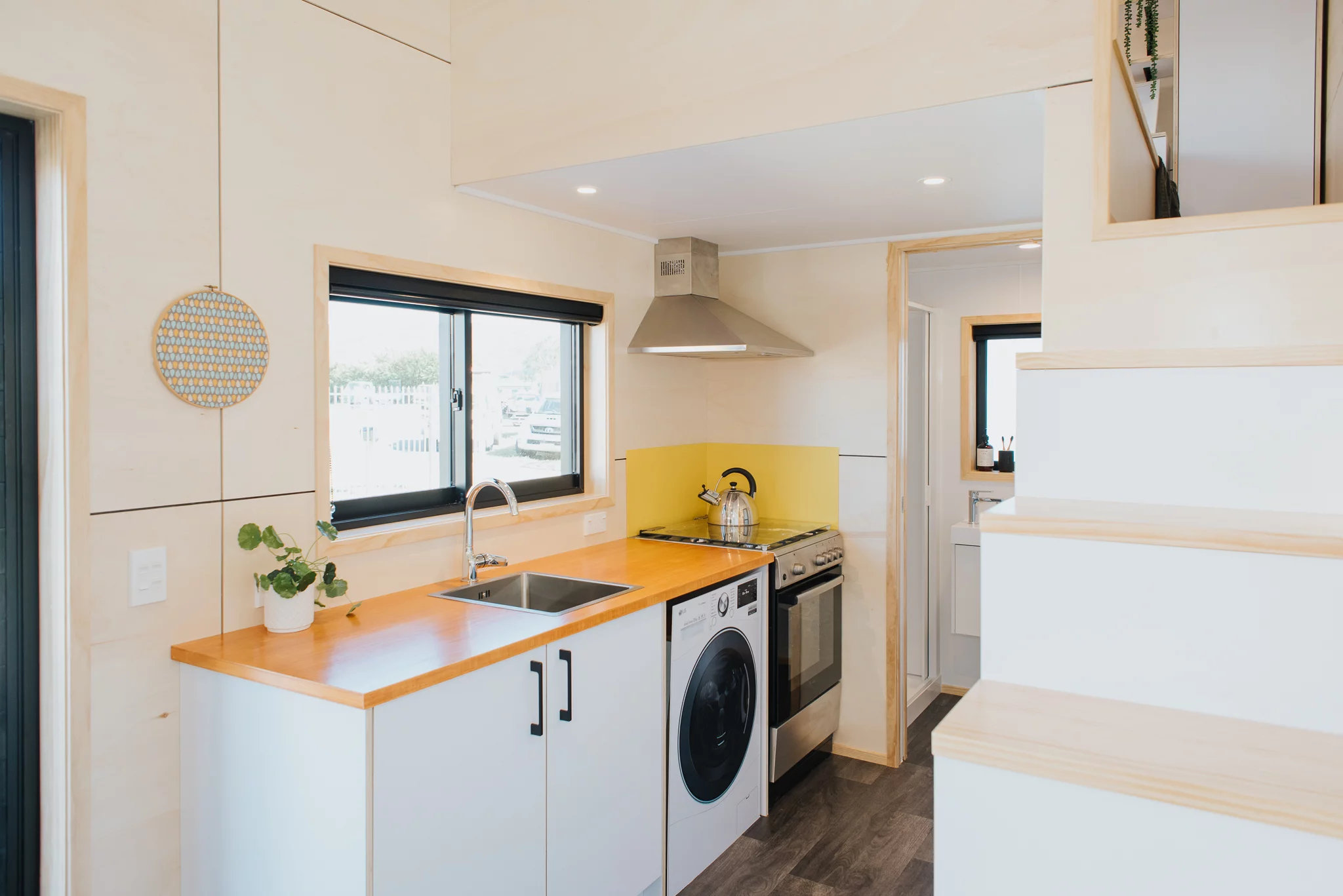 The Dreamweaver Tiny House's kitchen includes a washing machine