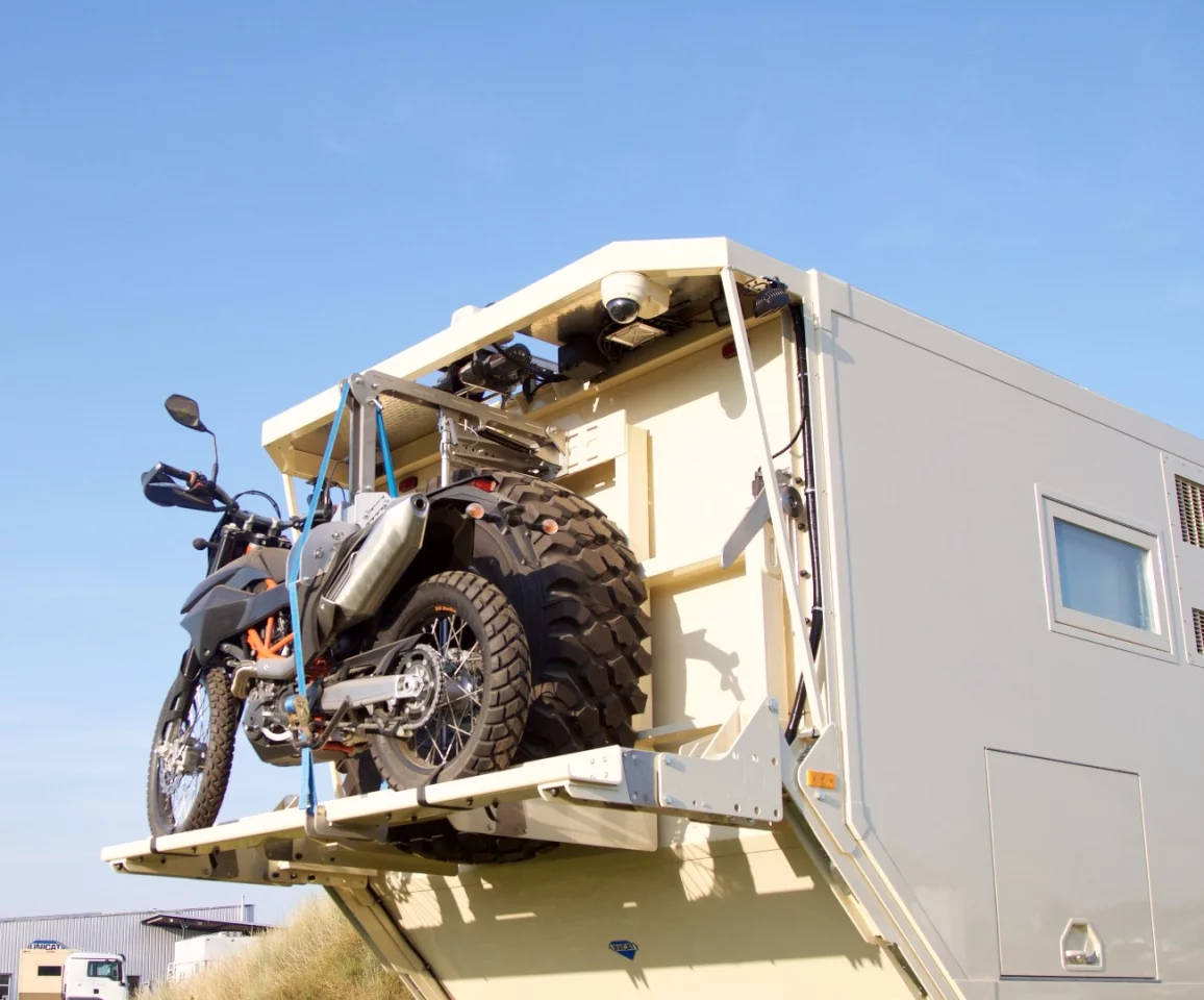 When you're driving a huge six-wheeler, we imagine having the option of something small, quick and nimble is nice to have. Unicat offers motorcycle storage on a winch-operated rear lift