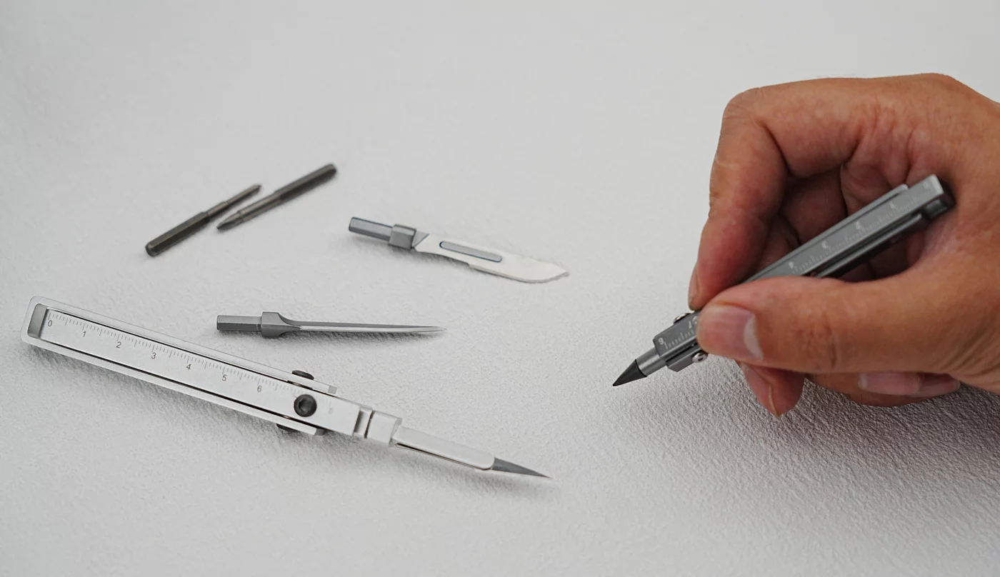 Standard kit includes a single black pen nib, a fixed knife, two craft blades, a ruler, glowing tritium vials, plus Phillips and flat-head screwdriver bits