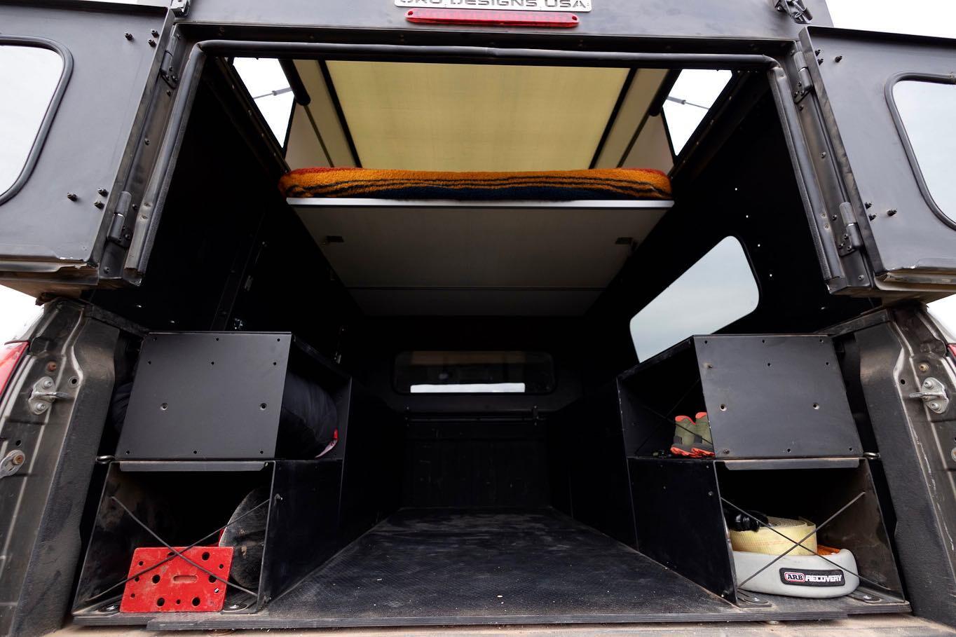 Inside the Oru Bruin camper with sleeping platform set up and Viato storage units installed on the bed