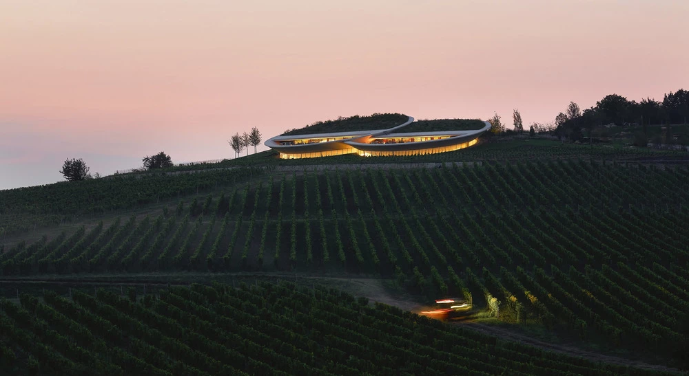 At sunset, the reflective underside of the structure glows softly against the hillside