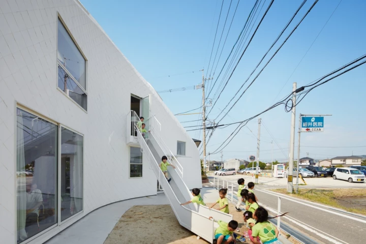A slide descends from the upstairs floor to an outdoor play area in front of the building