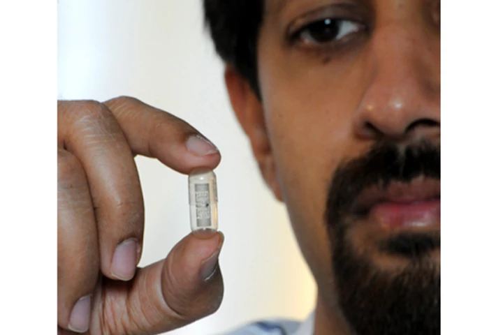 Rizwan Bashirullah holds a pill capsule designed to signal when a patient has swallowed it (Image: Ray Carson, UF News Bureau)