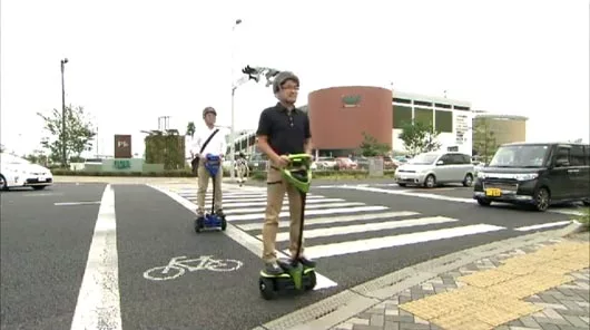 Test subjects ride the Toyota Winglet personal mobility robot on public sidewalks and road crossings in Japan