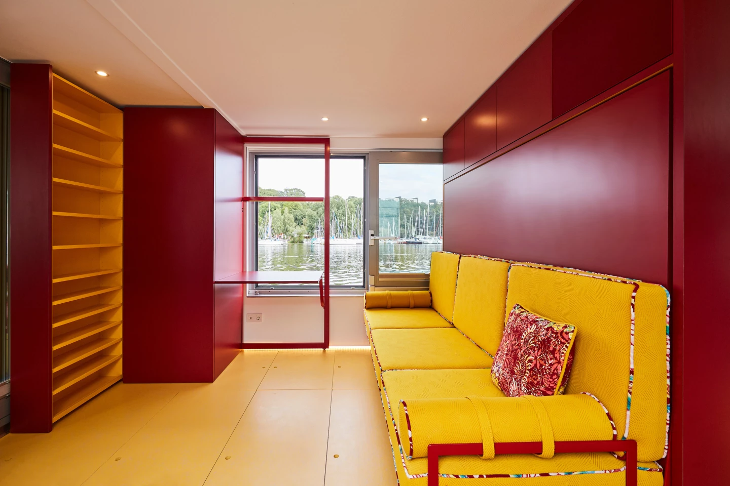 The Fàng Sōng's living room includes a large sofa bed, shelving, and a small work space overlooking a window