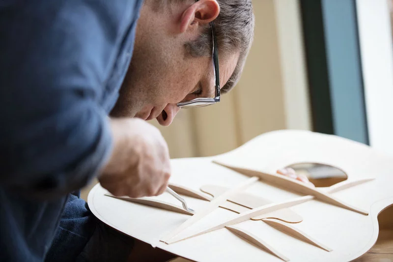 Taylor's master designer Andy Powers works on fan braces extending out from the center V-brace of an acoustic guitar's soundboard