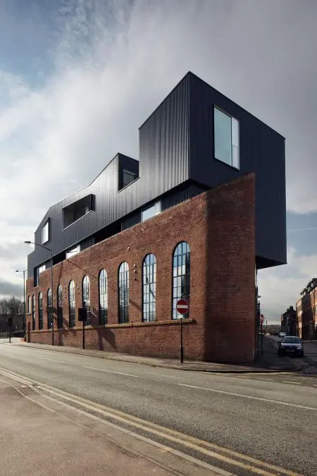 From architects Project Orange comes this fascinating extension on top of an old Victorian industrial brick building. The new black roof literally cuts through the original shell with the parasite completely overwhelming its host