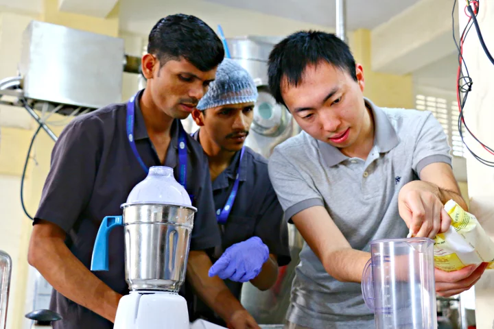 MIT graduate student Tonghan Gu (right) works with technicians at a facility in Vasai, India, to produce a batch of ready-to-use therapeutic food
