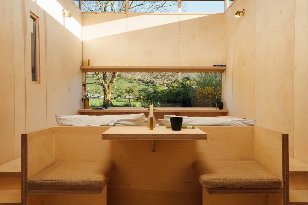 A kitchen and built-in table form a sitting space, while the bed sits on a raised platform