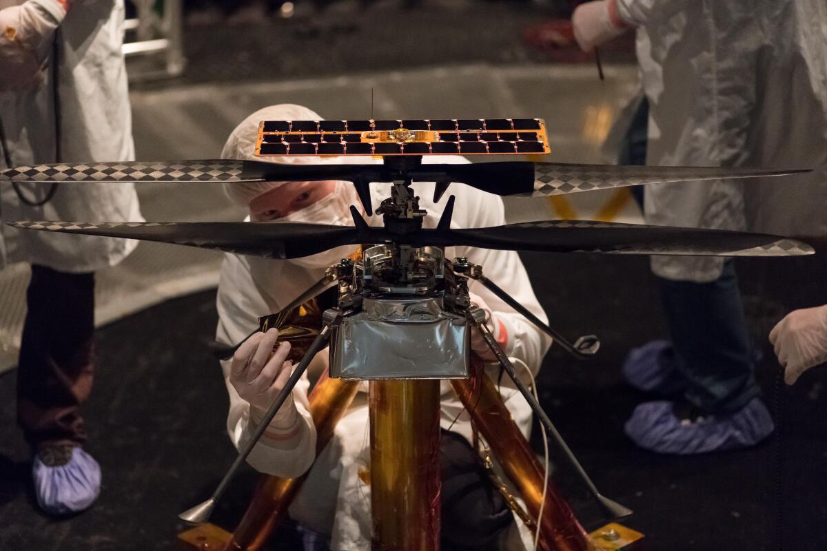 NASA engineers cover the main body of the Mars Helicopter in a protective thermal film