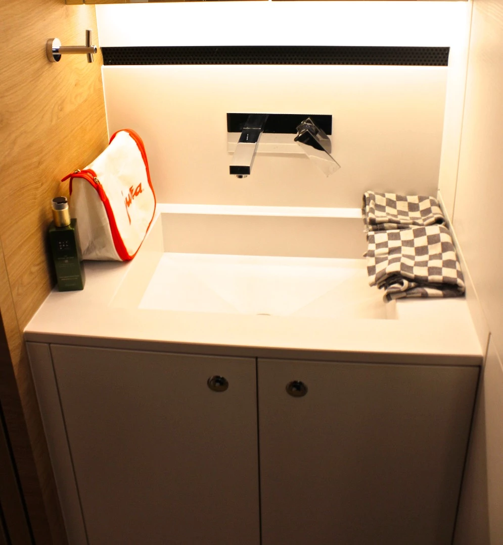 The sink stands across the hall from the separated toilet and shower