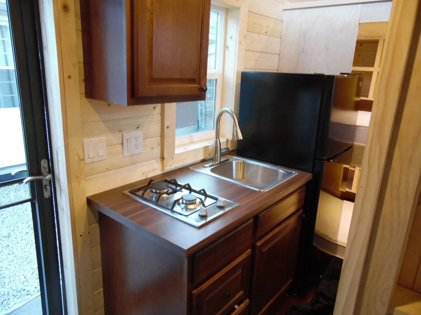 The kitchenette includes a propane double-burner and sink, storage space, and fridge/freezer