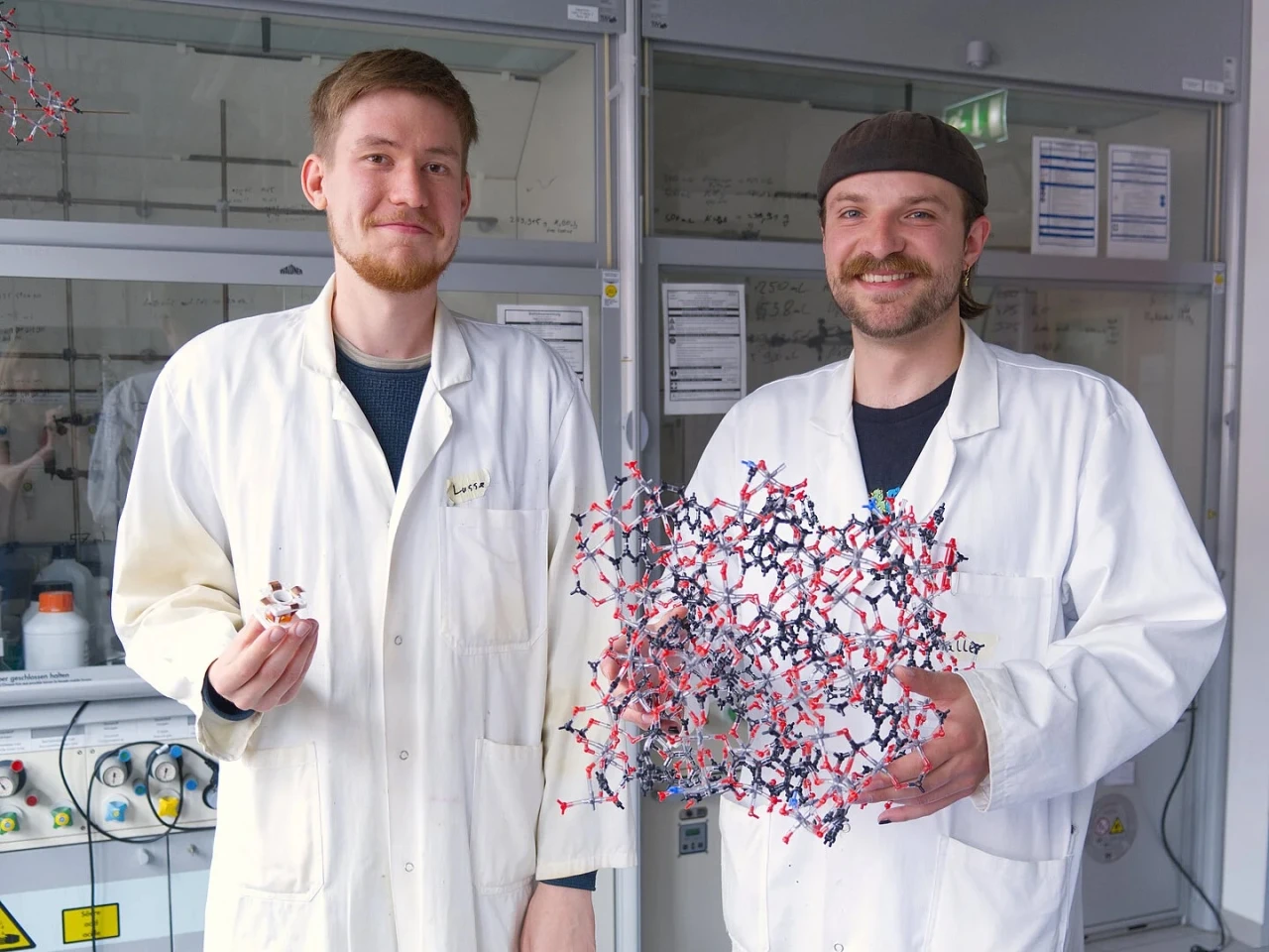 Lasse Wegner (left) and Kalle Mertin (right) present a prototype water-harvesting cell and a model of the MOF developed for atmospheric water harvesting and cooling