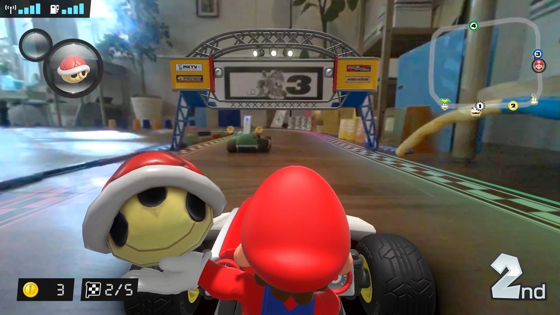 In Mario Kart Live: Home Circuit, the view on the Nintendo Switch screen is a mix of virtual characters and items laid over the real world camera feed from the remote-controlled kart