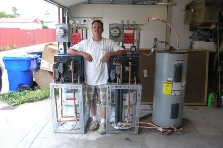 A prototype water heater system that uses cold water to make hot water pictured with Slater's assistant, David Dawson