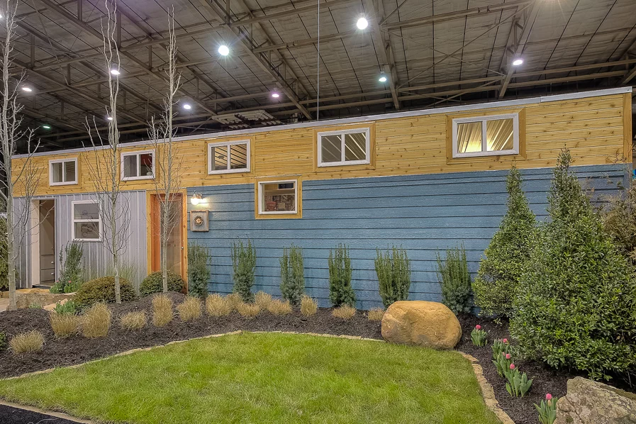 The container home is clad in lap siding, with a rim of cedar and some metal siding sections