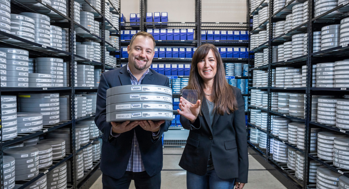 Brad Collar (left) and Vicky Colf (right), of Warner Bros., compare the differences between storing the same data on reels of film and glass slides