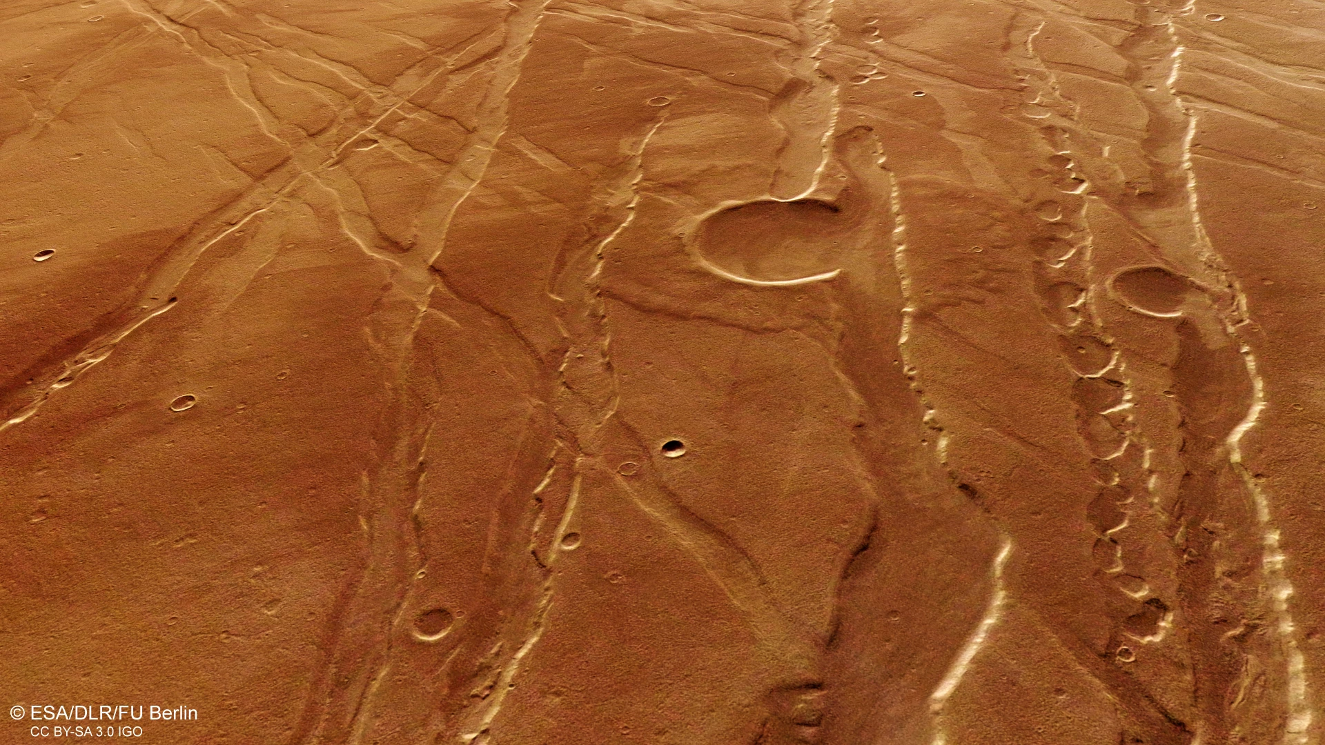 Perspective view of features in the Ascuris Planum region of Mars, including graben running in various directions, breached impact craters and pit chains (Credit: ESA/DLR/FU Berlin, CC BY-SA 3.0 IGO)