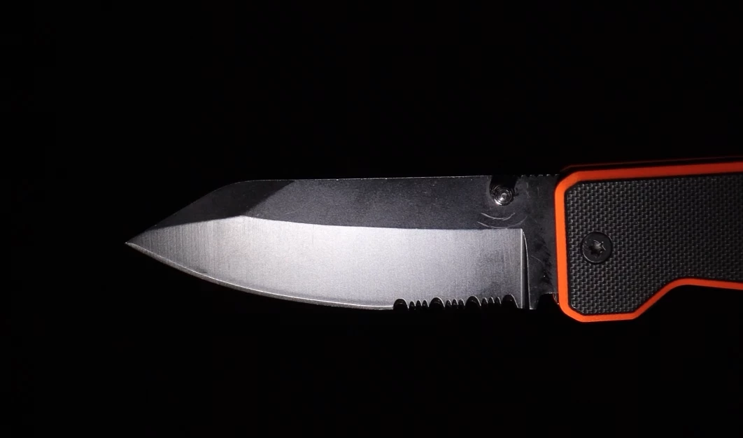 The high carbon steel knife blade has a thumb stud opener, drop point tip and straight/serrated edge