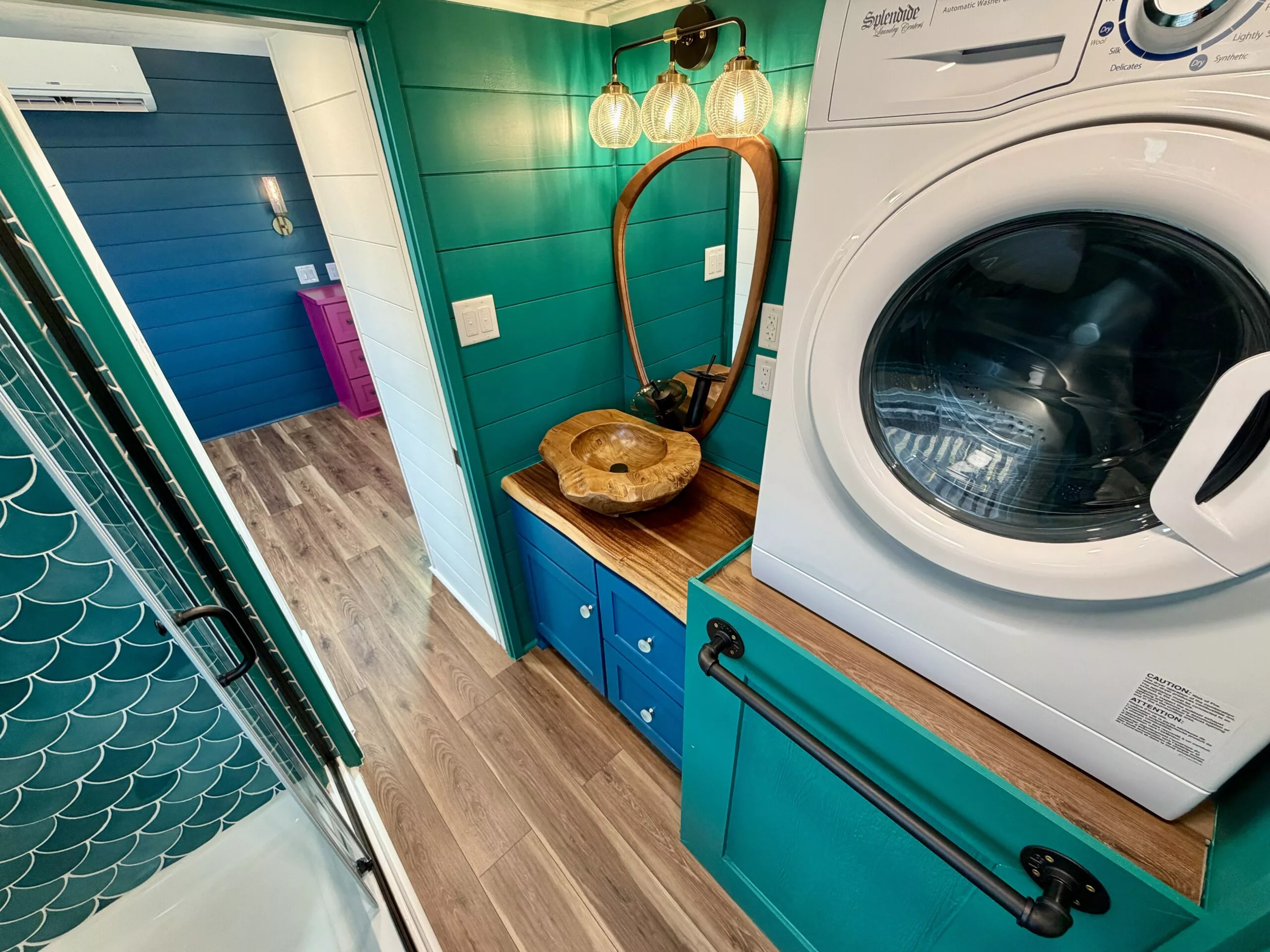 The Seawillow's bathroom includes colorful tiling, plus a glass-enclosed shower, a flushing toilet, an unusual teak sink, and a washer/dryer
