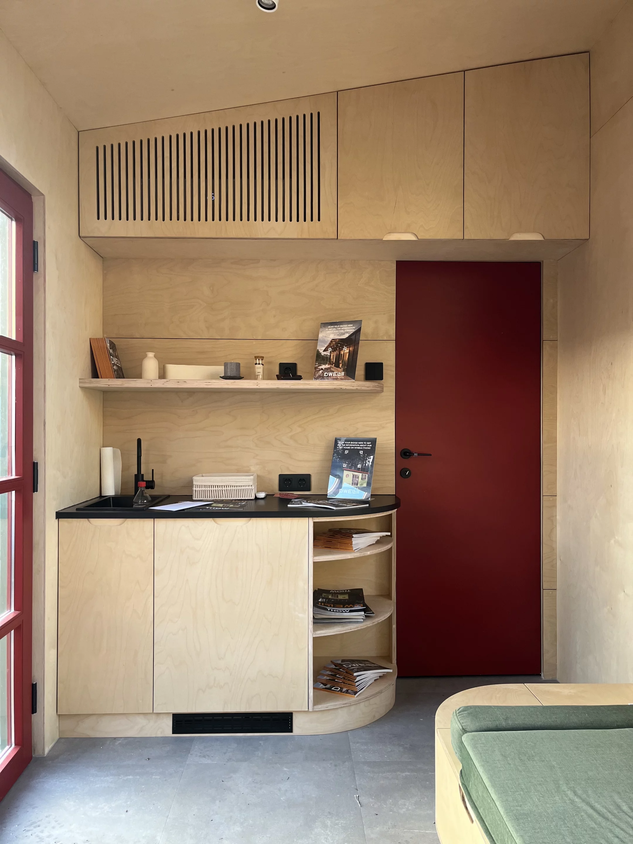 The THOW's kitchen is compact and includes a sink, cabinetry, and a two-burner stove