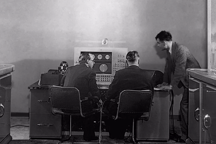 Turing (right) at the console of the Ferranti Mark I