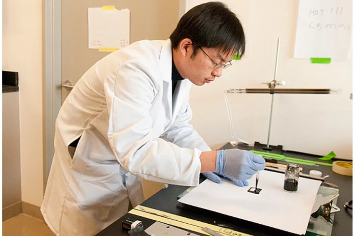 Researcher Bing Hu paints a small square of ordinary paper with an ink that will deposit nanotubes on the surface that can then be charged with energy to create a battery