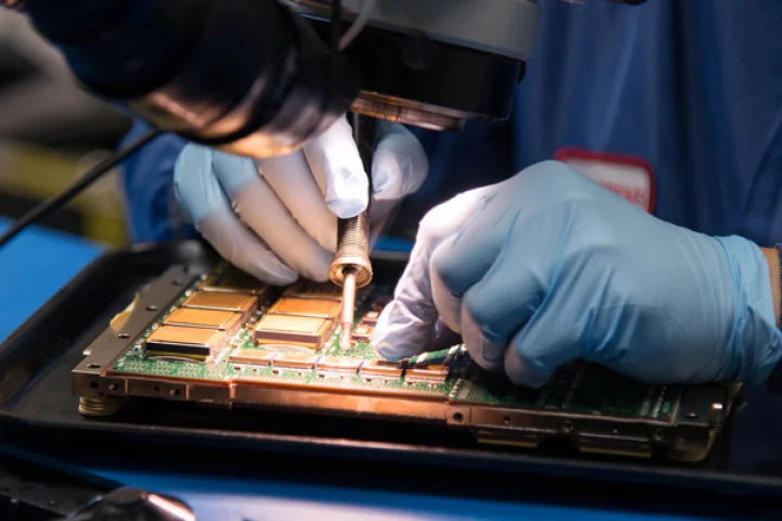 A technician soldering components in a RAD5545 single-board computer