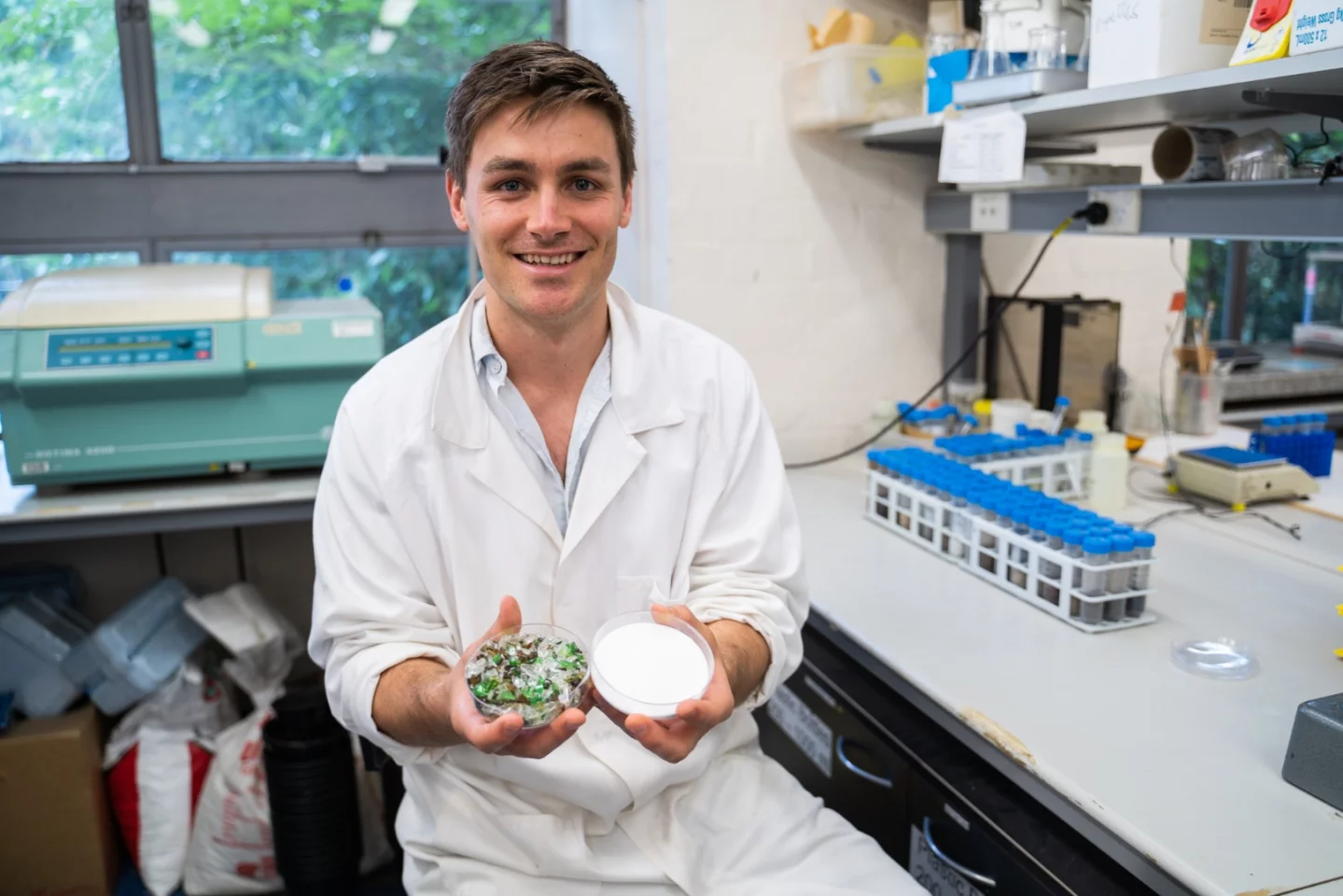PhD candidate Rhys Pirie with glass dishes containing waste glass and the silicate end product
